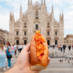 Mano che tiene un lobster roll Mason's davanti al Duomo di Milano