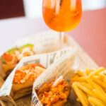Lobster roll Mason's con patatine fritte e uno spritz sul tavolo